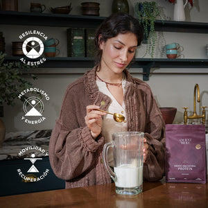 Woman preparing a protein shake with a package of Brave Ancestral Protein powder in a kitchen setting.