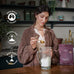 Woman preparing a protein shake with a package of Brave Ancestral Protein powder in a kitchen setting.